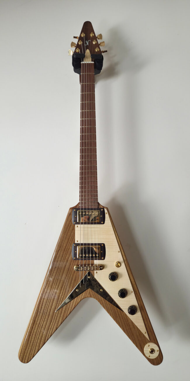 Mod&egrave;le de guitare Flying V type 1958 en fr&ecirc;ne torr&eacute;fi&eacute;, manche en &eacute;rable ond&eacute; et touche en noyer. Lutherie Thomas NO&Euml;L